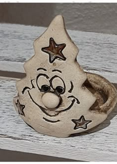 a clay face sitting on top of a white wooden bench with stars around it's eyes