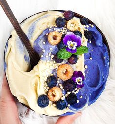 a person holding a blue plate with food on it and a spoon in the bowl