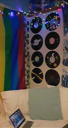 a laptop computer sitting on top of a bed next to a rainbow wall hanging above it