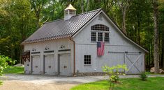 a white barn with an american flag on the roof