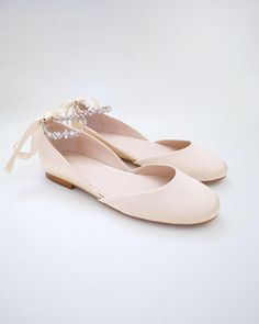 a pair of women's shoes with bows and pearls on the toe, all in pale pink