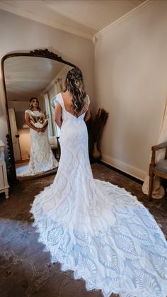 a woman in a wedding dress looking at herself in the mirror