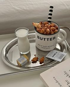 a tray with a cup of milk and some croissants next to a book