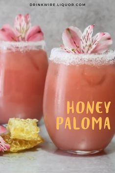 two glasses filled with honey paloma drink next to some flowers and gold flakes