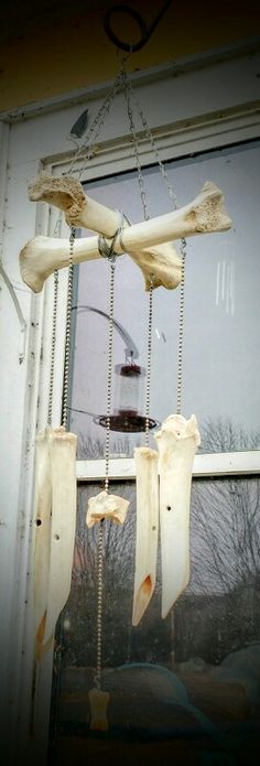 some kind of wind chime hanging in front of a window with chains attached to it