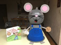 a cake made to look like a mouse with a cookie in its hand and a book on the table