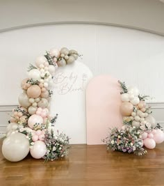 balloons and flowers are arranged in the shape of an arch for a baby's first birthday party