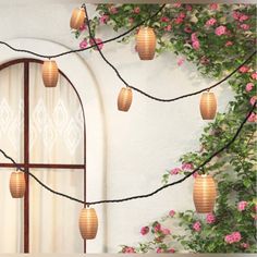 a window with pink flowers on it and some paper lanterns hanging from the windowsill