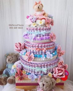 a teddy bear sitting on top of a cake made out of diapers and ribbons