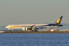 a large jetliner sitting on top of an airport tarmac next to the ocean