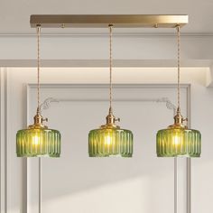 three green glass pendant lights hanging from a ceiling