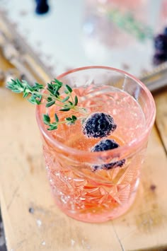 a close up of a drink in a glass with ice and berries on the rim