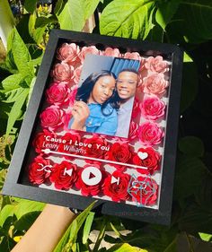 someone holding up a valentine's day photo in front of some flowers and greenery