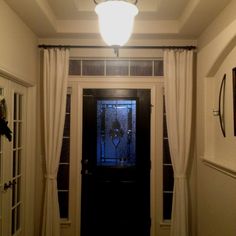 a black door with white curtains and a light above it