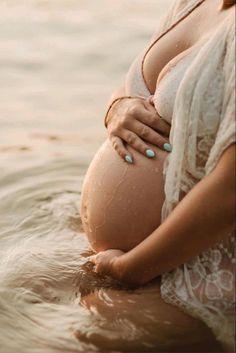 a pregnant woman standing in the water with her belly wrapped around her waist and wearing jewelry