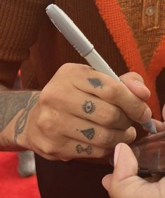 two people with tattoos on their hands and one holding a cell phone