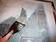 a person is using a brush to paint a piece of paper on the wall with newspaper clippings