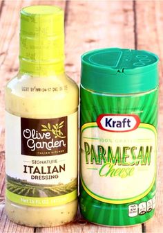 two bottles of dressing next to each other on a wooden table, one containing parmesan cheese and the other containing olive garden