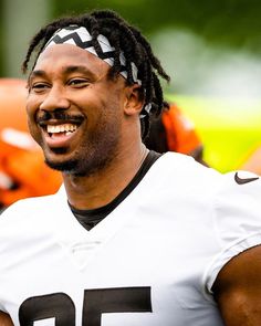 a man with dreadlocks on his head smiles at the camera while wearing a football uniform