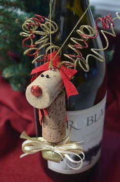 a wine bottle with a cork animal hanging from it's side next to a christmas tree