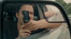 a man taking a photo in the side mirror of a car with his camera attached