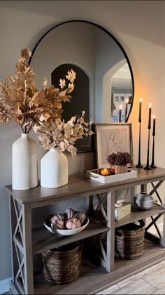 a table with vases, candles and plates on it in front of a mirror