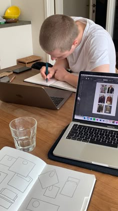 a young man is doing something on his laptop while sitting at the table in front of him