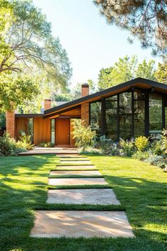 a modern house in the middle of a lush green yard with stepping stones leading up to it