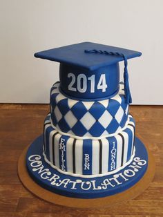 a graduation cake is decorated with blue and white checkered icing on a wooden table