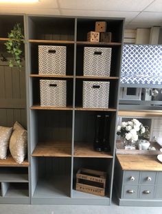 some shelves with baskets and boxes on them in a room that is painted blue, white and grey