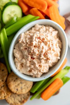 a plate with crackers, carrots, celery and cucumbers