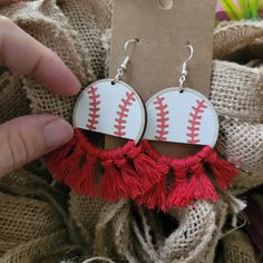 the earrings are decorated with red tassels and baseball stitched on it's sides