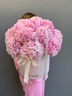 a woman holding a large bouquet of pink flowers