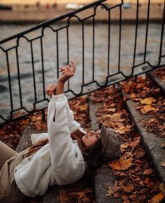 a woman laying on the ground with her hand up in the air and looking at something