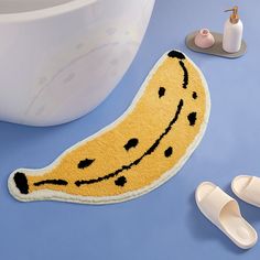 a bath mat with a smiley face drawn on it next to slippers and a sink