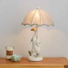 a white duck lamp on top of a wooden table next to a jar of candles