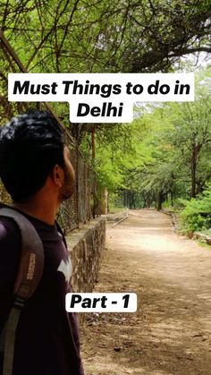 a man standing in front of a stone wall with trees and bushes behind him, the words must things to do in delhi part 1