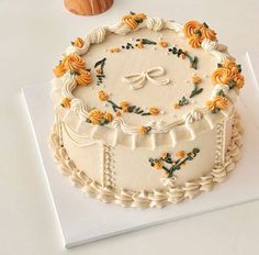 a decorated cake sitting on top of a white table next to an orange and yellow pumpkin