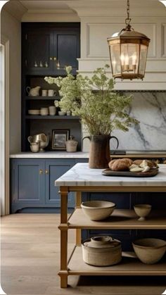 a kitchen island with plates and bowls on it in front of a light hanging from the ceiling