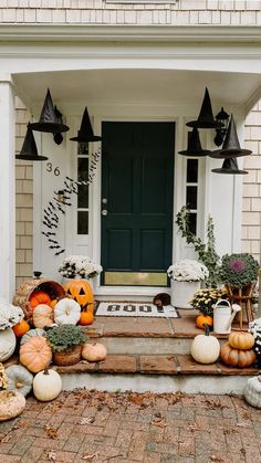 pumpkins and gourds on the front steps of a house with black lanterns