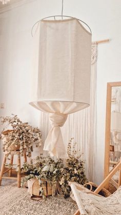 a white lamp hanging from the ceiling in a room filled with furniture and decor items