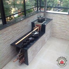 an outdoor kitchen with pots and pans on the stove top, in front of a large window