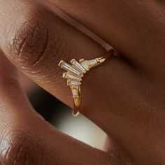 a woman's hand holding a gold ring with three baguettes on it