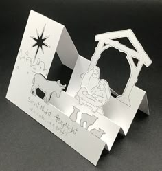 an origami nativity scene is displayed on a black surface with white paper