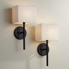 two lamps mounted on the wall next to each other, one is white and the other is black