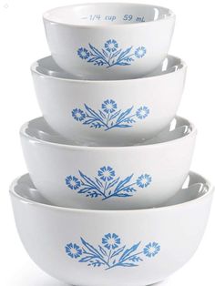 four bowls with blue flowers on them stacked in a pyramid shape, one is empty and the other has no lid