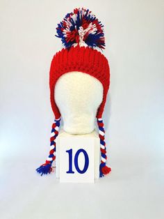 a red, white and blue knitted hat sitting on top of a table number 10