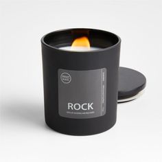 a black candle that is sitting next to a white background with the word rock on it