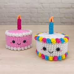 two crocheted birthday cakes sitting on top of a wooden table next to each other