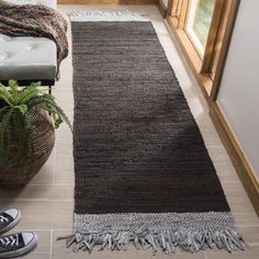 a black and white rug on the floor next to a plant in a potted planter